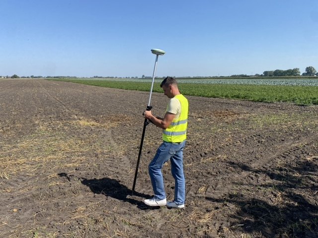 Odbiornik GNSS RTK Leica na tyczce podczas pomiaru w polu